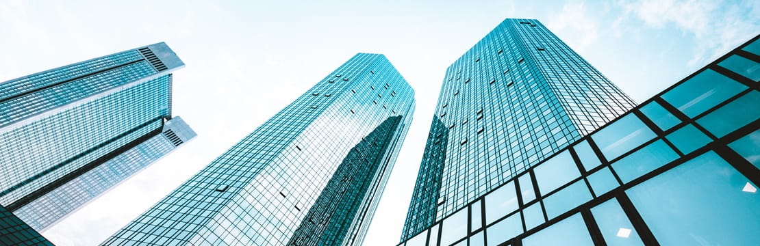 	Low wide-angle view looking up to modern skyscrapers in business district on a beautiful sunny day with blue sky and clouds